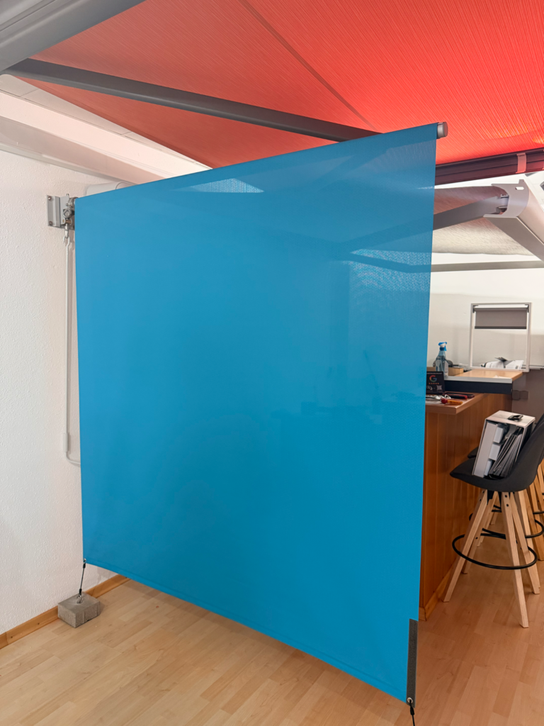 Skuggi in der Ausstellung Blaue Sichtschutzwand in einem modernen Innenraum.